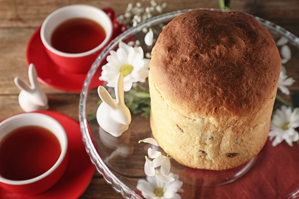 decorated glass stand with easter cake and cups of tea on wooden table - Кулич быстрого приготовления