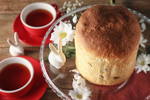 decorated glass stand with easter cake and cups of tea on wooden table - Кулич быстрого приготовления