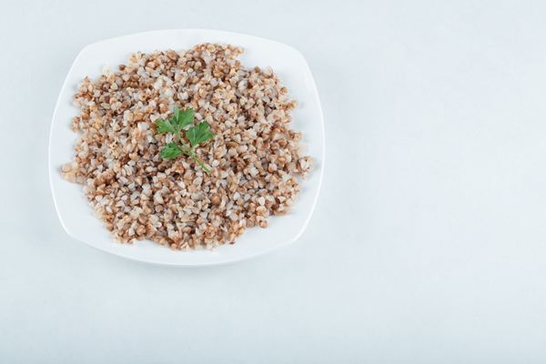 delicious buckwheat with greens on white plate - Конвертики из лаваша с гречкой и грибами, постный стол