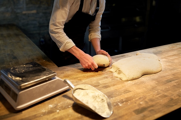 food cooking baking and people concept chef or baker portioning dough with bench cutter at bakery - Кулич быстрого приготовления