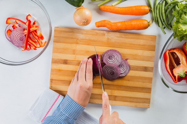 hands cutting onions in the kitchen - Минтай с овощами