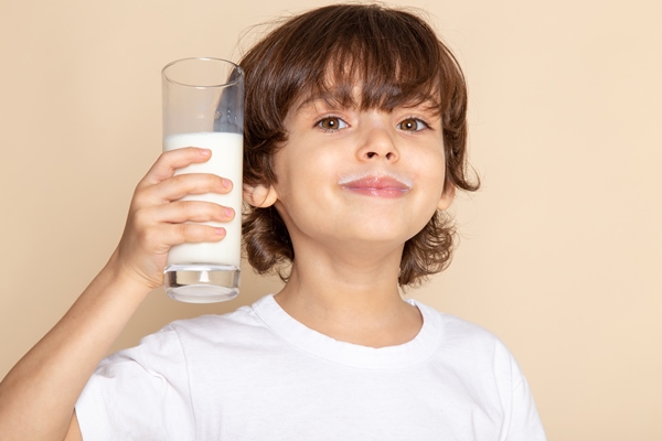 little kid adorable drinking whole white milk smiling on pink - Особенности питания детей