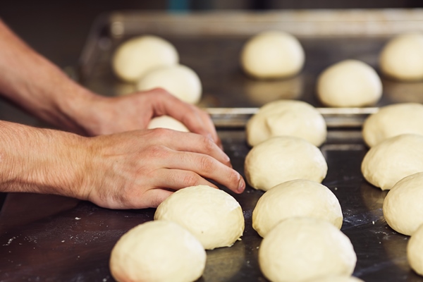 pastry chef forms round buns from dough and spreads them on metal pan - Жаворонки двойные и одиночные