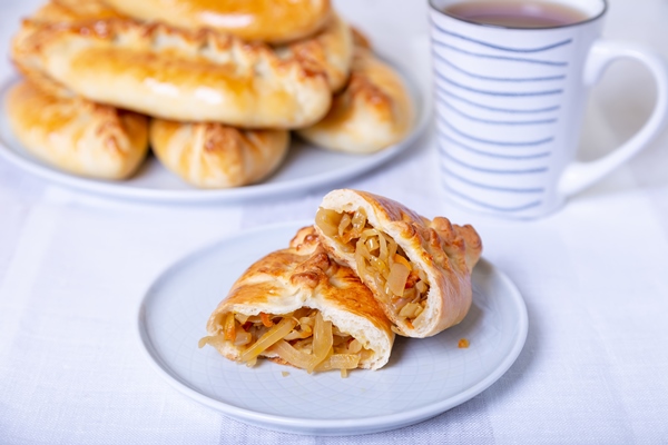 pies pirozhki with cabbage homemade baking traditional russian and ukrainian cuisine in the background is a dish with pies close up - Начинка из квашеной капусты с грибами