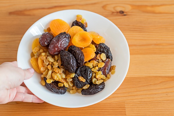 plate with dried fruits on a wooden table useful food dates dried apricots prunes raisins - Лечебный стол (диета) № 3 по Певзнеру: таблица продуктов и режим питания