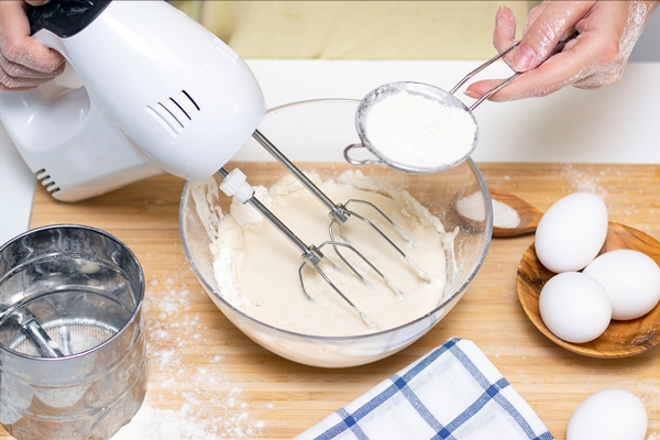 process of making dough for pancakes with ingredients on a light table eggs and flour are whipped with a - Испанское пасхальное печенье "Цветы"