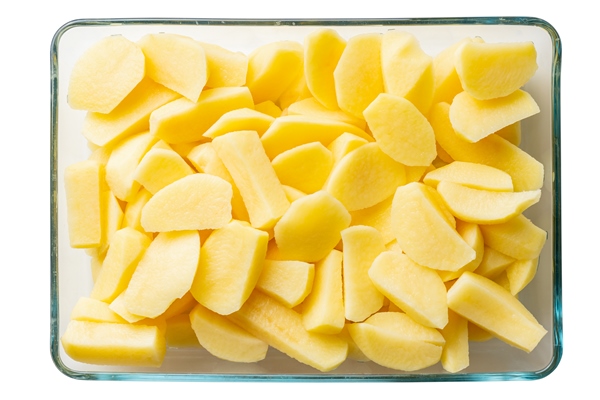 raw cut potatoes in a transparent bowl isolated on white background - Запечённый морской окунь с картофелем