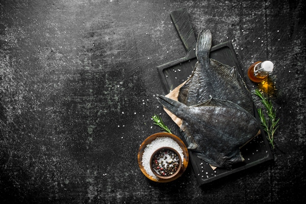 raw fish flounder on a cutting board with rosemary and spices - Как очистить камбалу