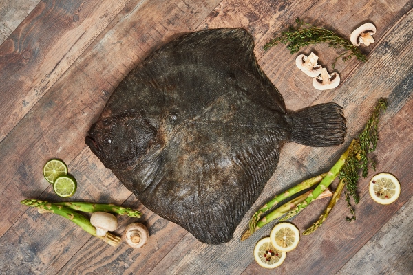 raw uncooked flatfish with lemons asparagus herbs mushrooms and spices on wooden table european plaice top view - Камбала соте