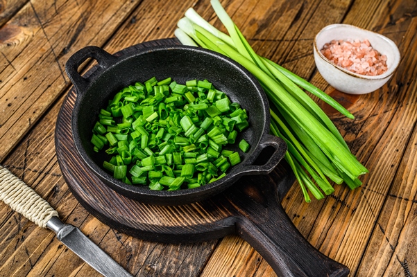 sliced green onions in a pan wooden background top view - Цукини, фаршированные кашей и баклажанами