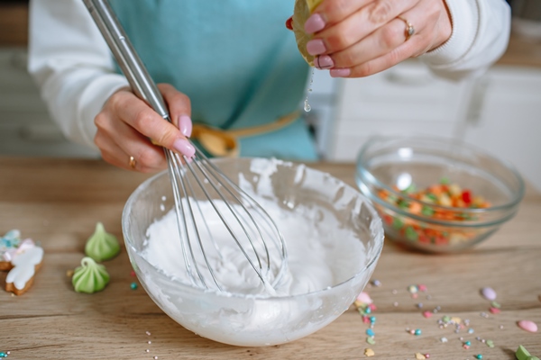 the smiling woman cook whips up the icing for the easter cake with a whisk and squeezes a lemon into it - Куличи александрийские