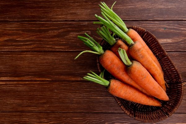 top view basket plate with carrots wooden background with copy space 1 - Морковный сок со сливками