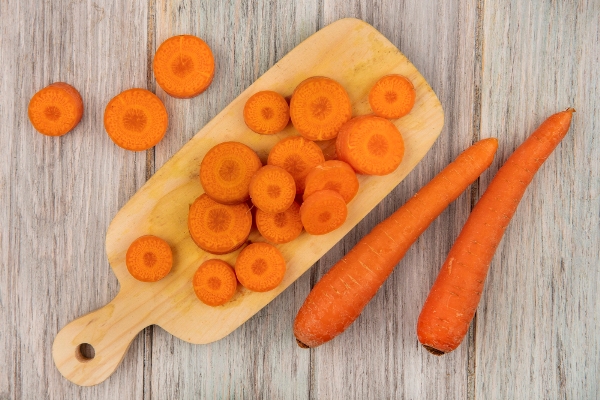 top view of orange chopped carrots on a wooden kitchen board with carrots isolated on a grey wooden wall - Начинка из моркови