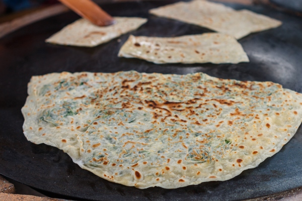 turkish woman prepares gozleme traditional dish in the form of flatbread stuffed with greens and cheese 1 - Постные лепёшки с зеленью (кутабы)