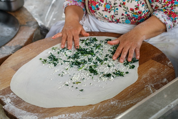 turkish woman prepares gozleme traditional dish in the form of flatbread stuffed with greens and cheese - Постные лепёшки с зеленью (кутабы)