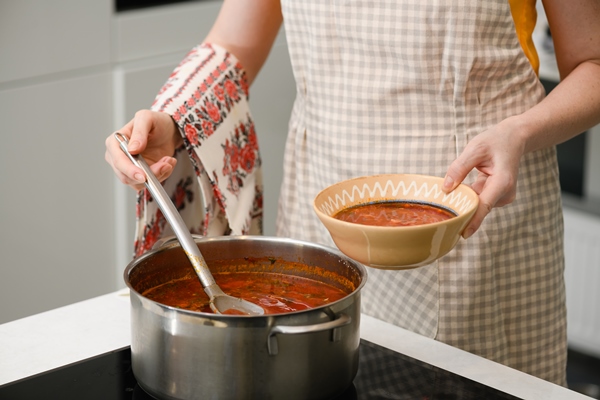 a woman pours freshly prepared ukrainian borscht onto a plate - Борщ из лопуха