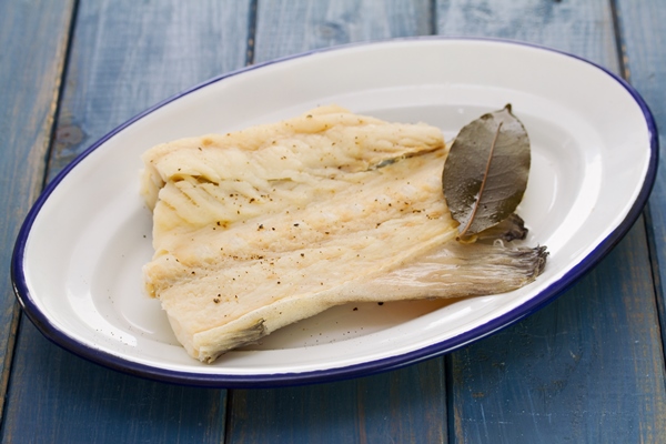 boiled cod fish on white dish on wooden table - Острый рыбный суп с томатом