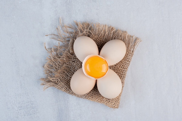 bundle of eggs and egg yolk in a shell on marble table - Пирожки с черемшой и яйцом