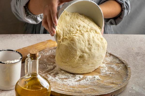 female chef putting pizza dough on wooden board - Пирожки с черемшой и яйцом