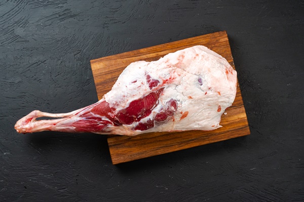 fresh raw lamb leg ready for roasting on wooden board top view - Кюфта-бозбаш