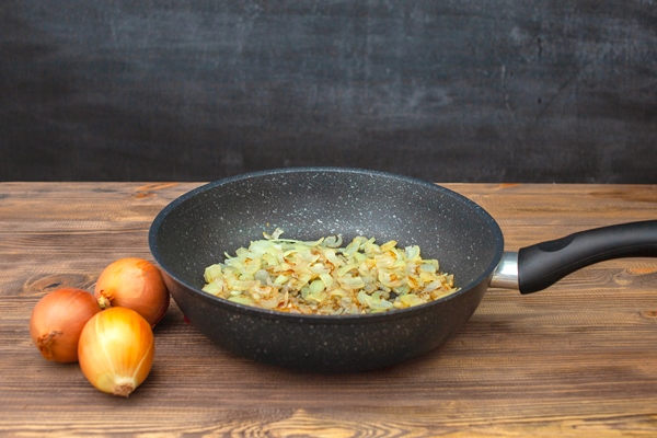 frying pan with fried onions three onions side by side chalk board in the background - Сныть тушёная