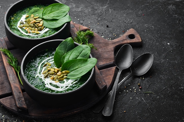 green spinach cream soup with cream and pumpkin seeds in a black bowl healthy food top view rustic style - Холодный суп из лебеды и щавеля