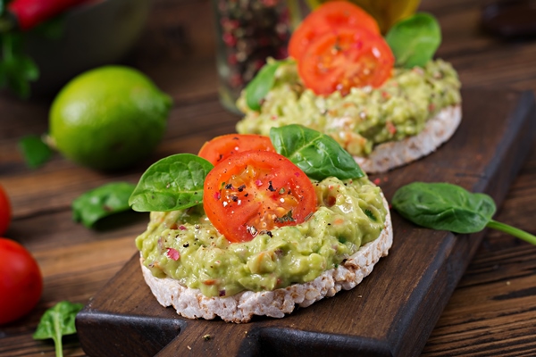 healthy breakfast sandwich crisp bread with guacamole and tomatoes on a wooden table - Паштет из черемши с томатами