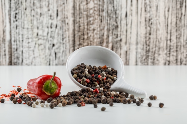 mixed peppercorns in a plate with red pepper side view on white and wooden grunge wall - Маринованные бутоны черемши