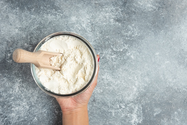 woman hand holding glass bowl of flour on marble 1 - Голубцы с черемшой