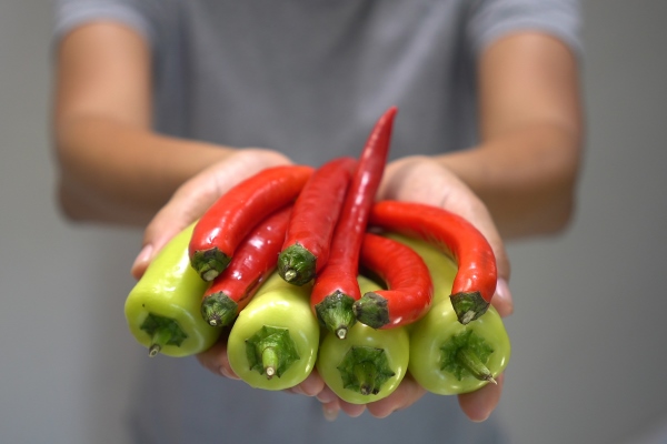 woman hand holding red and green chili bell pepper - Острый рыбный суп с томатом