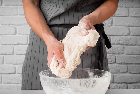 woman kneading dough over bowl - Пирожки с черемшой и яйцом