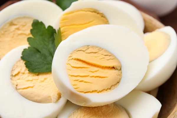 wooden bowl with fresh hard boiled eggs and parsley on table closeup - Пирожки с черемшой и яйцом