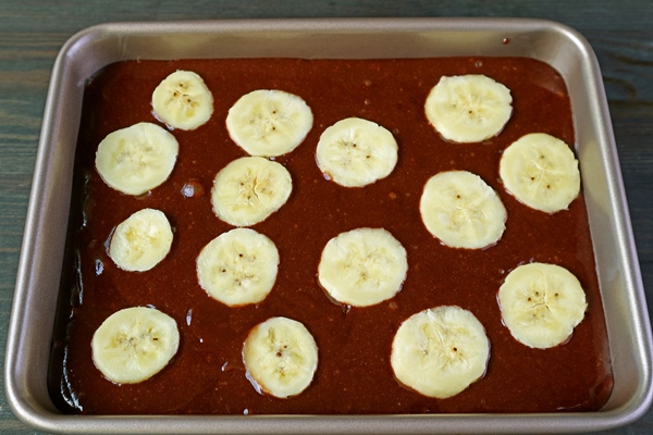 chocolate cake batter with cut ripe banana in a cake pan ready to bake - Шоколадный пирог с бананами