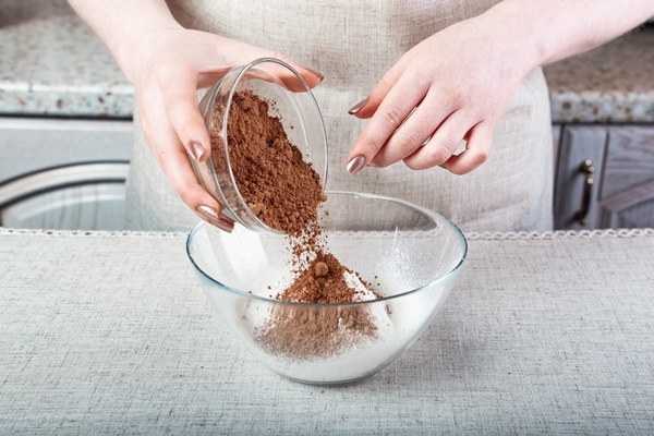 hands pouring cocoa powder into a glass bowl with flour 1 - Шоколадный пирог с бананами
