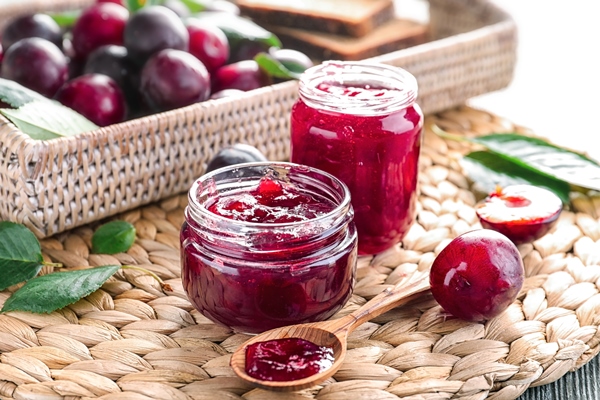 small glass jars with tasty homemade plum jam on wicker mat - Сливовое варенье с орехами