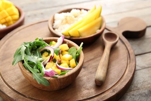 bowl with tasty mango salad on wooden table - Фруктовая острая закуска, постный стол