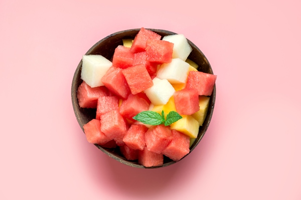 fruit salad of watermelon melon and mango in coconut bowl on pink background 2 - Мексиканский острый фруктовый салат