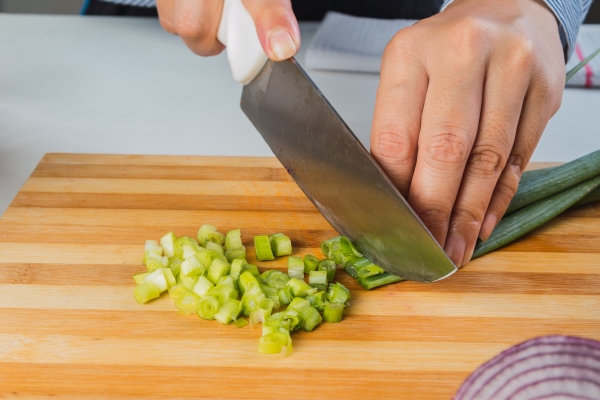 chopped green onions on wooden board closeup - Окрошка с колбасой на квасе