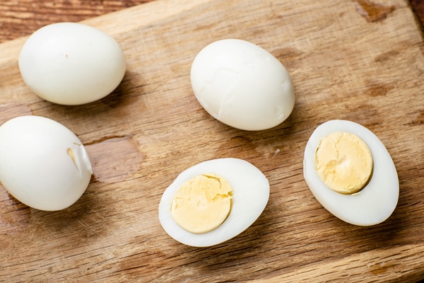 halves of boiled chicken eggs on a wooden background - Окрошка с колбасой на квасе