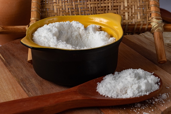 tapioca flour in a black bowl and on a wooden spoon - Запеканка из капусты