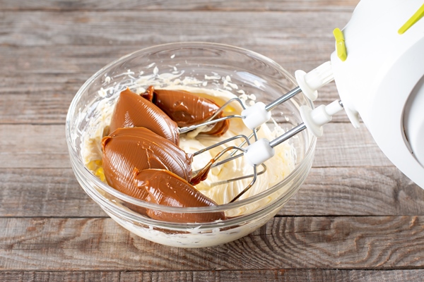 butter and boiled condensed milk in a glass bowl with a mixer making cake cream - Вафельный торт со сгущёнкой