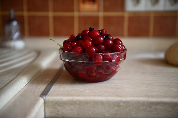 close up food picture of fresh sweet delicious ready to eat ripe cherry berries in transparent glass bowl on the kitchen counter high angle view - Вареники с вишней