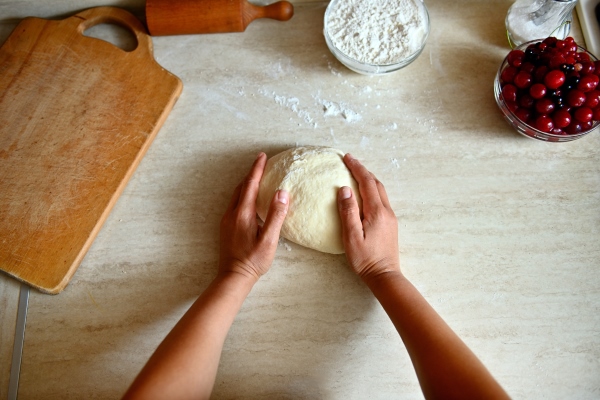 high angle view of female hands kneading dough on the kitchen countertop preparing delicious traditional ukrainian dumplings process of cooking dumplings step by step - Вареники с вишней