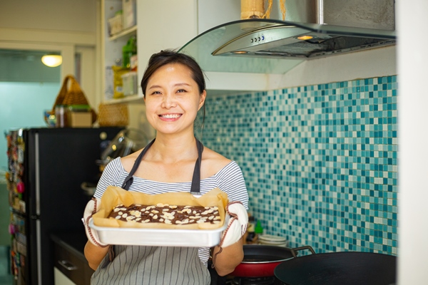 chinese woman holding fresh brownies chocolate after finished cooking food - Шоколадно-миндальный брауни