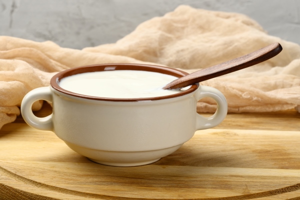 sour cream in a brown ceramic bowl with a wooden spoon on a table fermented milk useful product - Мясо по-французски