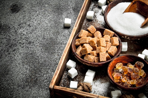 different kinds of sugar in bowls on a tray on a rustic background - Молочный сахар
