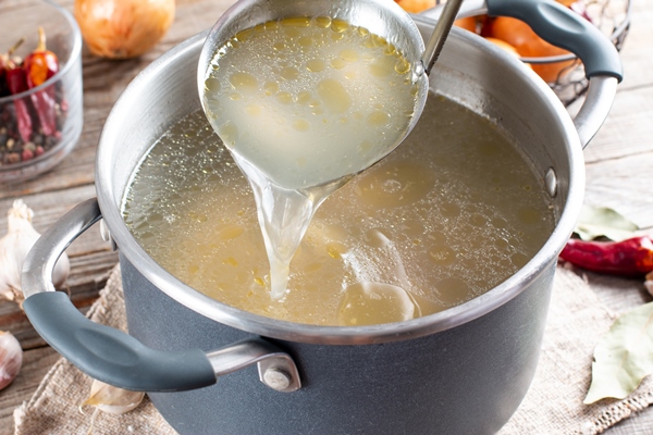 saucepan with bouillon with a ladle on the table bone broth - Свинина с каштанами и грибами