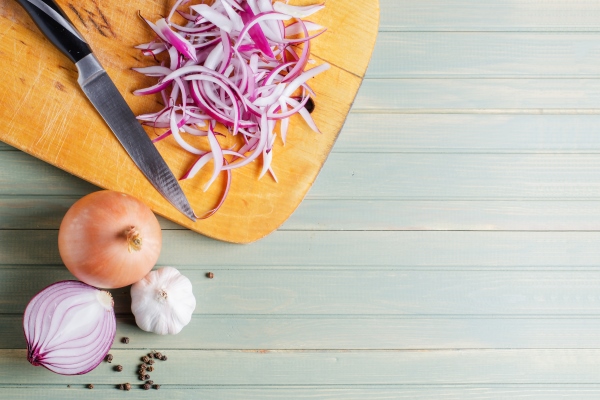 sliced red onion and kitchen knife on wooden board - Свинина с каштанами и грибами