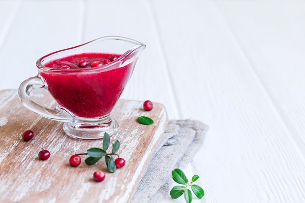 fresh lingonberry sauce in a gravy boat on a white wooden background - Клюквенный (или брусничный) взвар