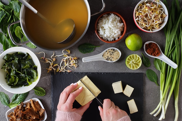 woman is cutting tofu into cubes for traditional japanese miso soup - Мисо суп